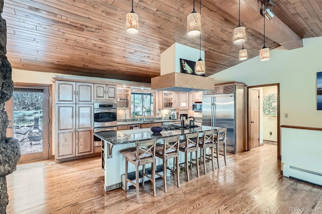 kitchen featuring a breakfast bar area, a sink, wood ceiling, vaulted ceiling, and appliances with stainless steel finishes