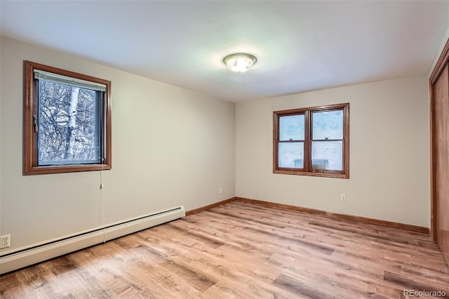 spare room featuring a baseboard heating unit, light wood-style floors, plenty of natural light, and baseboards