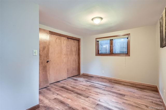 unfurnished bedroom with a closet, wood finished floors, and baseboards