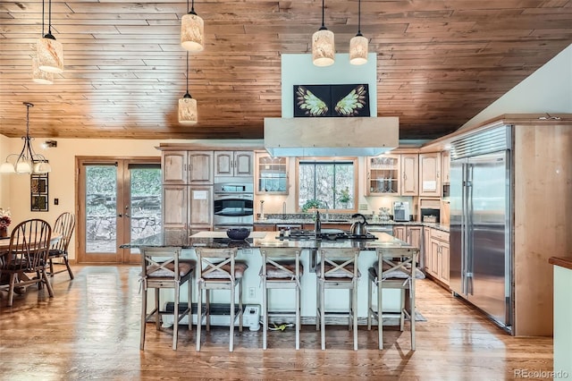 kitchen featuring a breakfast bar, wood ceiling, a healthy amount of sunlight, and appliances with stainless steel finishes