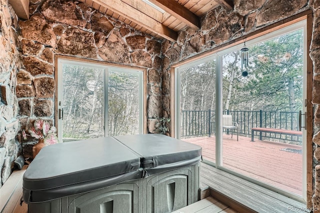 sunroom featuring a hot tub, a wealth of natural light, and beamed ceiling