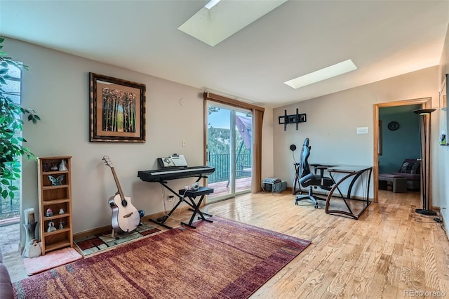 interior space with baseboards, a skylight, and wood finished floors