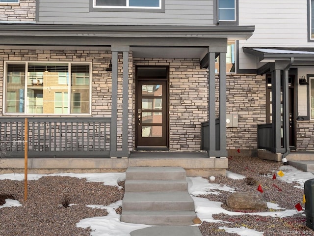 snow covered property entrance with a porch