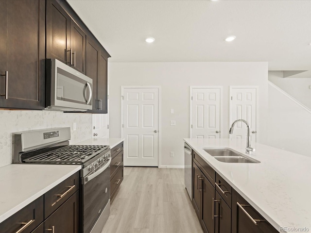 kitchen featuring appliances with stainless steel finishes, sink, backsplash, dark brown cabinetry, and light hardwood / wood-style flooring