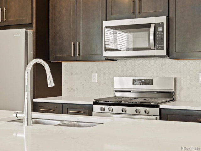 kitchen featuring stainless steel appliances, dark brown cabinets, sink, and backsplash