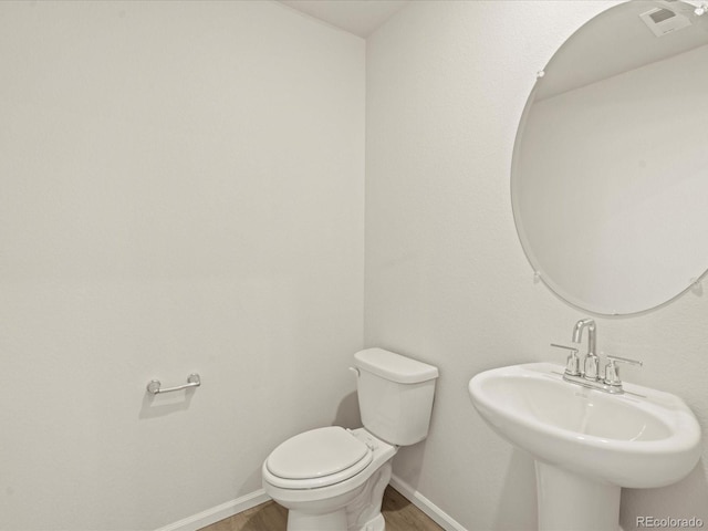 bathroom featuring wood-type flooring, toilet, and sink