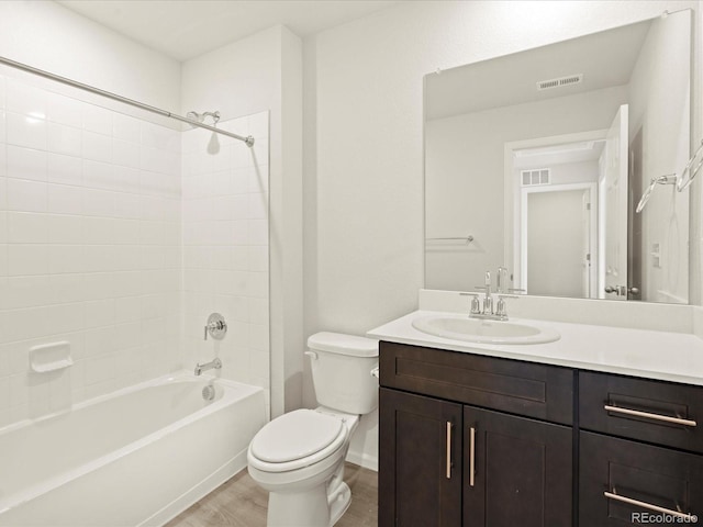 full bathroom with wood-type flooring, toilet, tiled shower / bath combo, and vanity