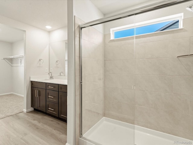 bathroom with hardwood / wood-style flooring, vanity, and a shower with shower door