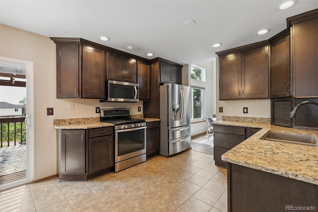 5040 Sweetgrass Ln, Colorado Springs, CO 80922 - kitchen featuring stainless steel appliances, a sink, dark brown cabinetry, recessed lighting, and light stone countertops