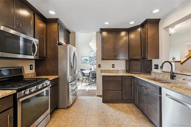 5040 Sweetgrass Ln, Colorado Springs, CO 80922 - kitchen featuring stainless steel appliances, a sink, dark brown cabinets, light stone counters, and light tile patterned floors