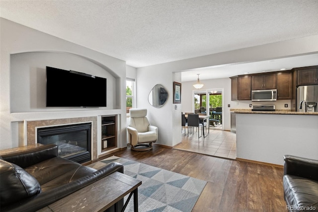 5040 Sweetgrass Ln, Colorado Springs, CO 80922 - living room featuring dark wood-style floors, a textured ceiling, a tile fireplace, and baseboards