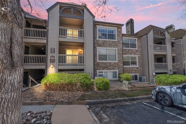 view of property with central AC unit and uncovered parking