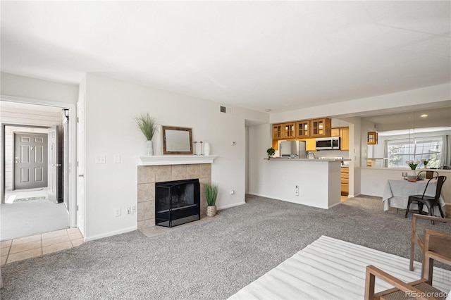 living area featuring carpet floors and a tiled fireplace