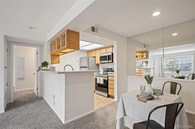 kitchen with stainless steel appliances, recessed lighting, light carpet, a peninsula, and light countertops