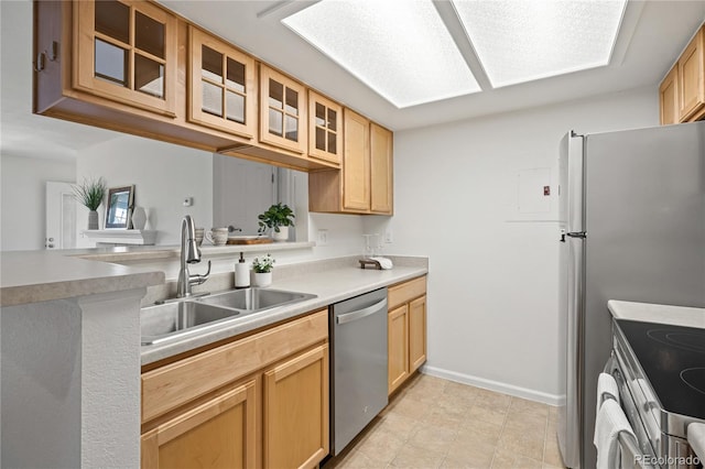 kitchen with appliances with stainless steel finishes, a sink, glass insert cabinets, light countertops, and baseboards