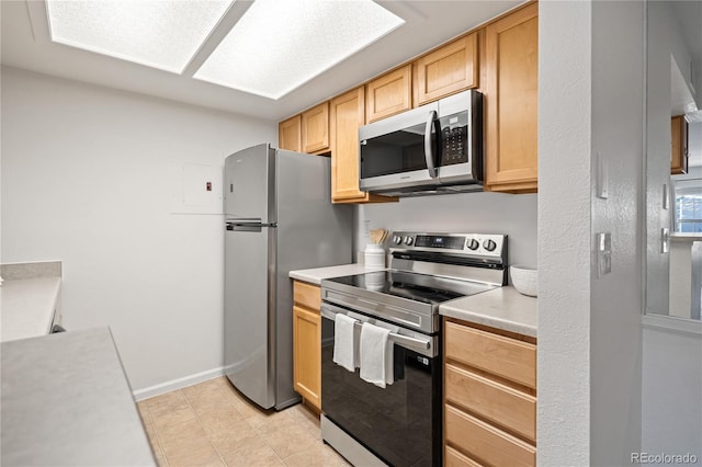 kitchen with appliances with stainless steel finishes, light brown cabinetry, and light countertops