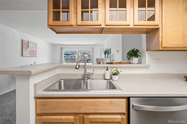 kitchen featuring dishwasher, a sink, light countertops, and glass insert cabinets
