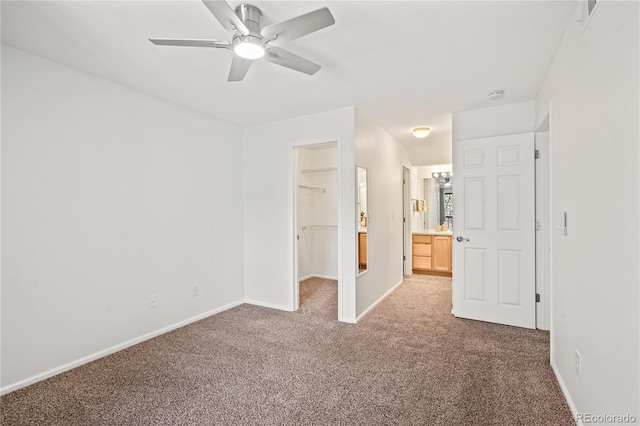 unfurnished bedroom featuring carpet flooring, a spacious closet, baseboards, and a closet