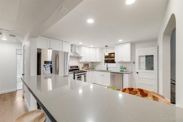 2090 Irving St, Denver, CO 80211 - kitchen featuring stainless steel appliances, wall chimney range hood, backsplash, a kitchen breakfast bar, and white cabinetry