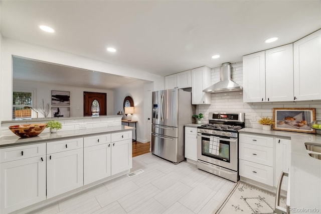 2090 Irving St, Denver, CO 80211 - kitchen featuring stainless steel appliances, wall chimney exhaust hood, white cabinets, backsplash, and recessed lighting