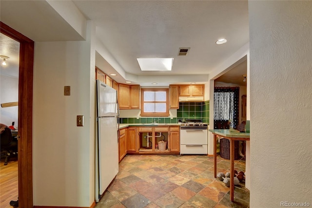 6805 Marshmerry Ln, Evergreen, CO 80439 - kitchen with white appliances, backsplash, light stone finish floors, a skylight, and under cabinet range hood