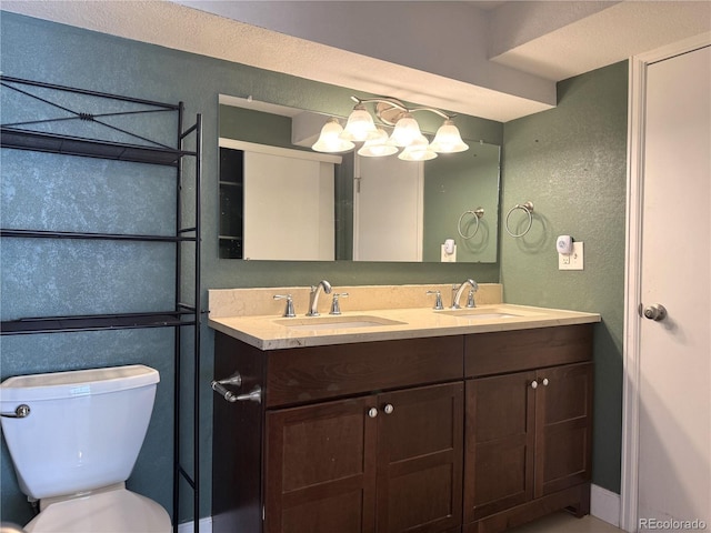 full bathroom with a sink, a textured wall, toilet, and double vanity