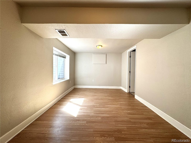 unfurnished room with baseboards, wood finished floors, and visible vents