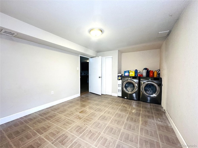 washroom with baseboards, visible vents, and washing machine and clothes dryer
