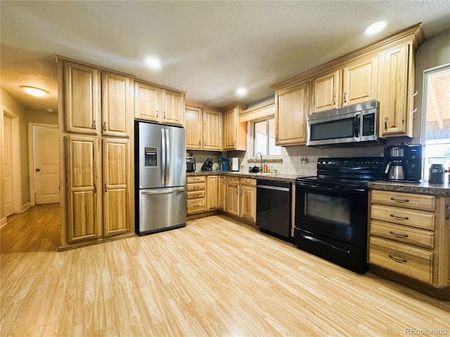 kitchen featuring backsplash, light wood finished floors, appliances with stainless steel finishes, and light brown cabinetry