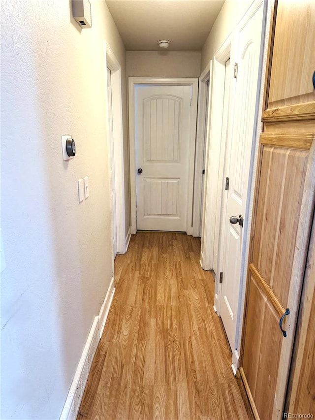 corridor with baseboards and light wood finished floors