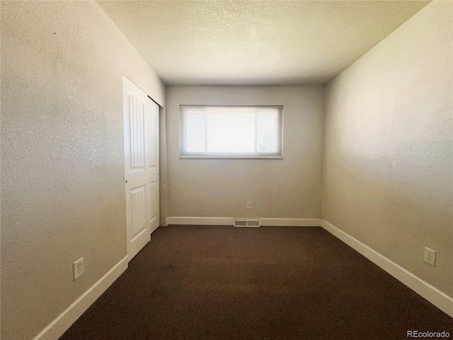 unfurnished room featuring visible vents, baseboards, and dark colored carpet