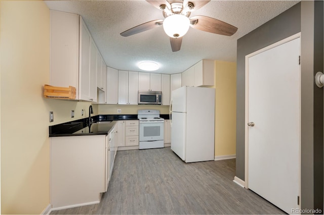 kitchen featuring white cabinetry, white appliances, light wood-type flooring, ceiling fan, and sink