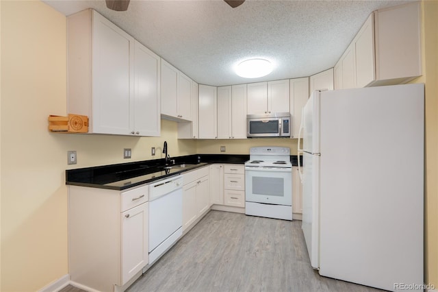 kitchen with light wood-type flooring, white appliances, and white cabinets