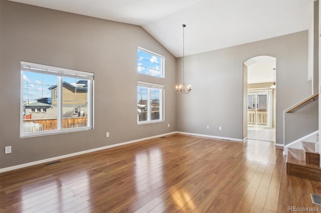 empty room with hardwood / wood-style flooring, high vaulted ceiling, and a notable chandelier