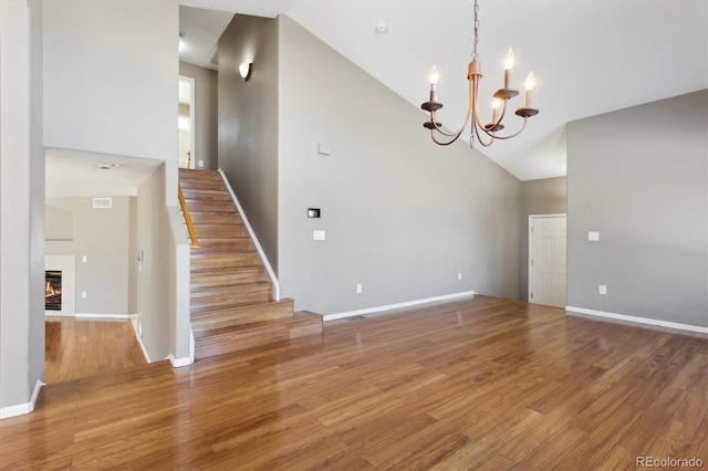 interior space with hardwood / wood-style flooring, a fireplace, a chandelier, and high vaulted ceiling