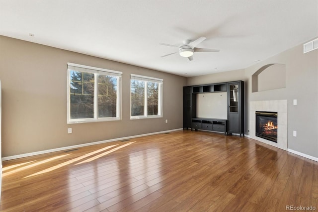 unfurnished living room with wood-type flooring, ceiling fan, and a fireplace