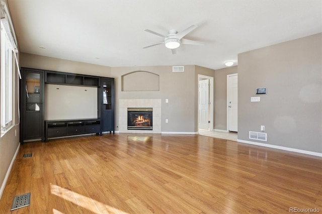 unfurnished living room with wood-type flooring, ceiling fan, and a fireplace