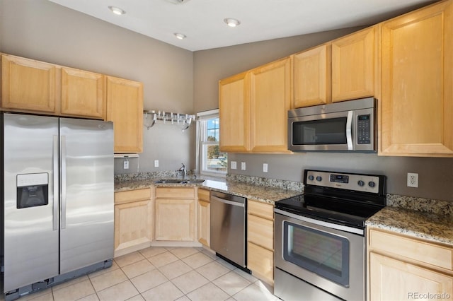 kitchen with light stone countertops, appliances with stainless steel finishes, and light brown cabinets