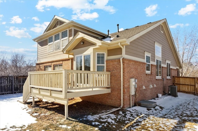 snow covered house featuring central air condition unit and a deck