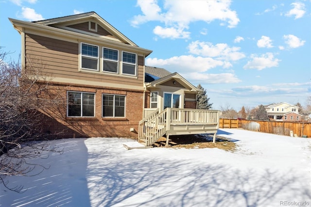 snow covered rear of property with a deck