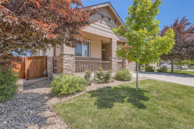 25561 E 5th Pl, Aurora, CO 80018 - view of property hidden behind natural elements with a porch, stone siding, and concrete driveway
