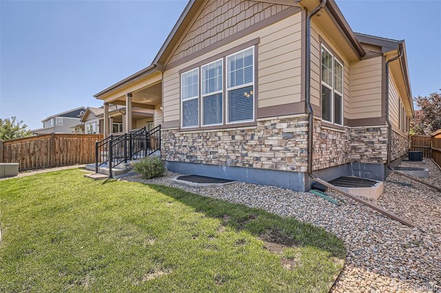 25561 E 5th Pl, Aurora, CO 80018 - view of side of home with stone siding and central AC unit