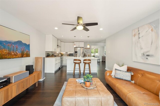 living room featuring ceiling fan, recessed lighting, and dark wood-type flooring