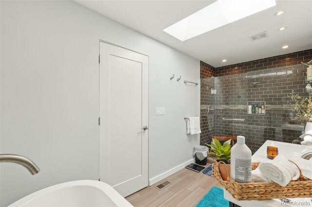 bathroom with visible vents, recessed lighting, wood finished floors, and a skylight