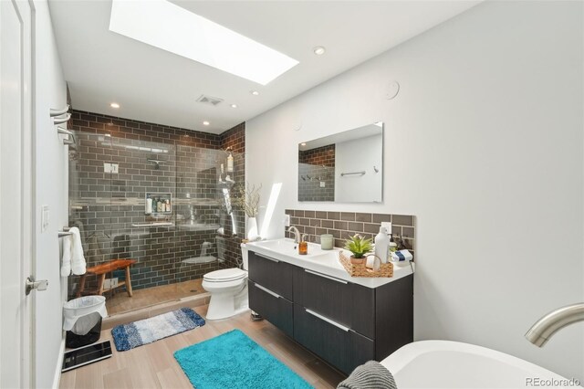 full bathroom with a tile shower, toilet, decorative backsplash, wood finished floors, and visible vents