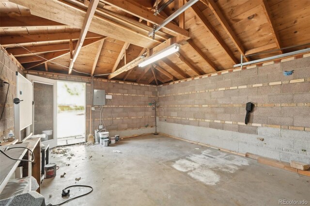 miscellaneous room with a garage, concrete flooring, and concrete block wall