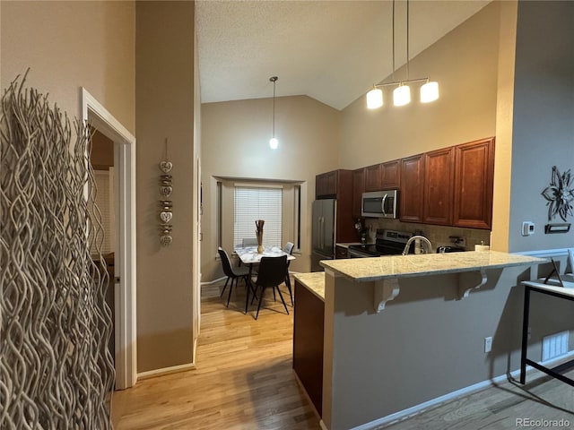 6887 S Dover Way, Littleton, CO 80128 - kitchen with stainless steel appliances, high vaulted ceiling, a breakfast bar, backsplash, and a peninsula