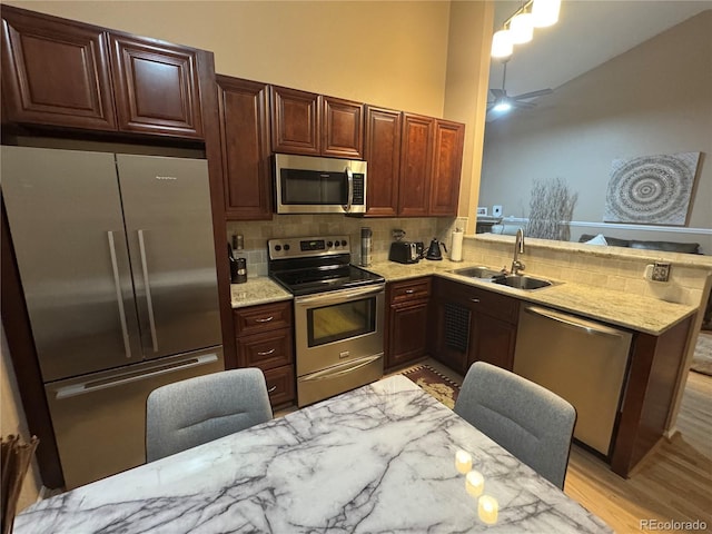 6887 S Dover Way, Littleton, CO 80128 - kitchen with appliances with stainless steel finishes, a sink, light wood finished floors, tasteful backsplash, and light stone counters
