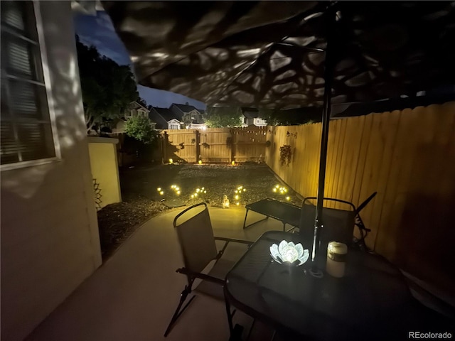 6887 S Dover Way, Littleton, CO 80128 - patio at night with a fenced backyard, outdoor dining area, and a patio