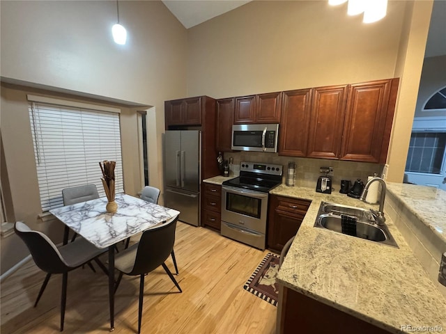 6887 S Dover Way, Littleton, CO 80128 - kitchen featuring appliances with stainless steel finishes, high vaulted ceiling, a sink, decorative backsplash, and light wood-type flooring